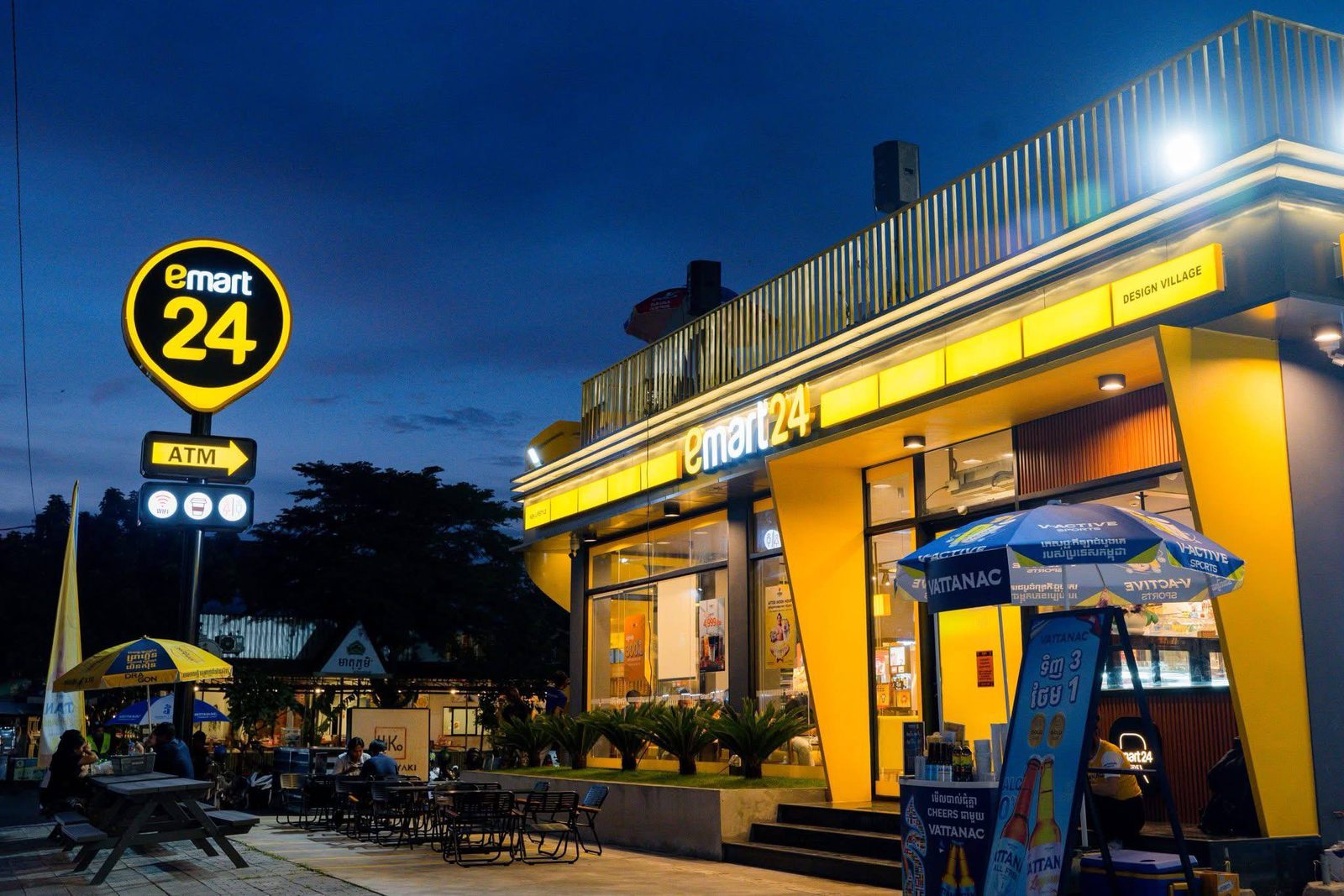The yellow emart24 storefront lit up at night with outdoor seating